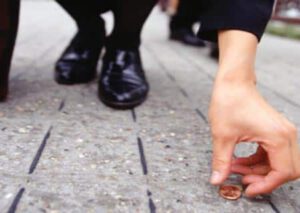 Businesswoman picking up penny on sidewalk, low section