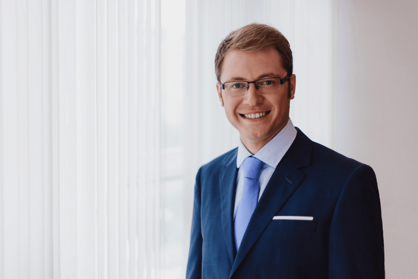 portrait of a smiling, blond financial advisor with glasses